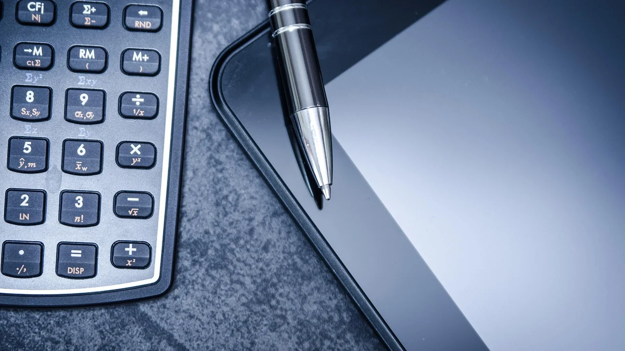 Calculadora, notas fiscais e planilha usados no controle tributário.