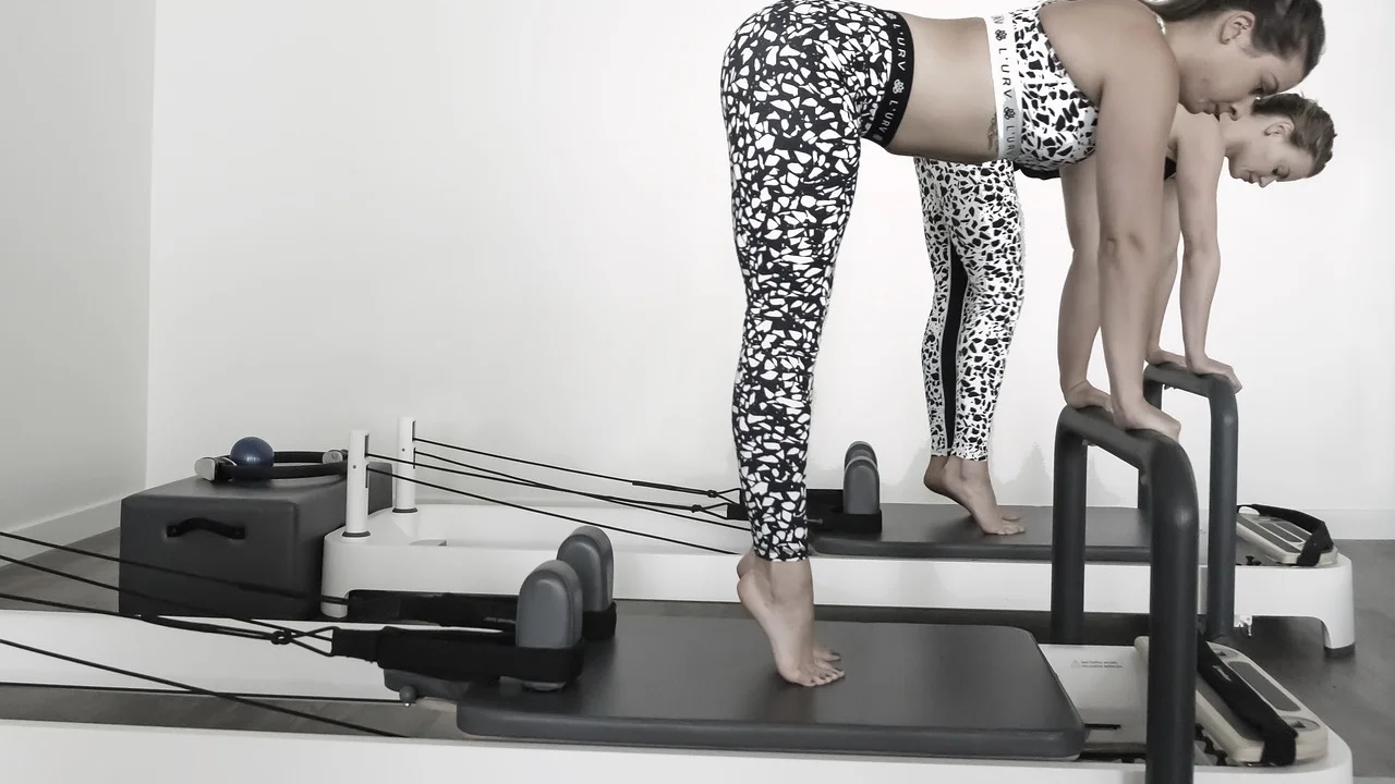 Pessoa iniciante realiza exercício de pilates com orientação profissional.