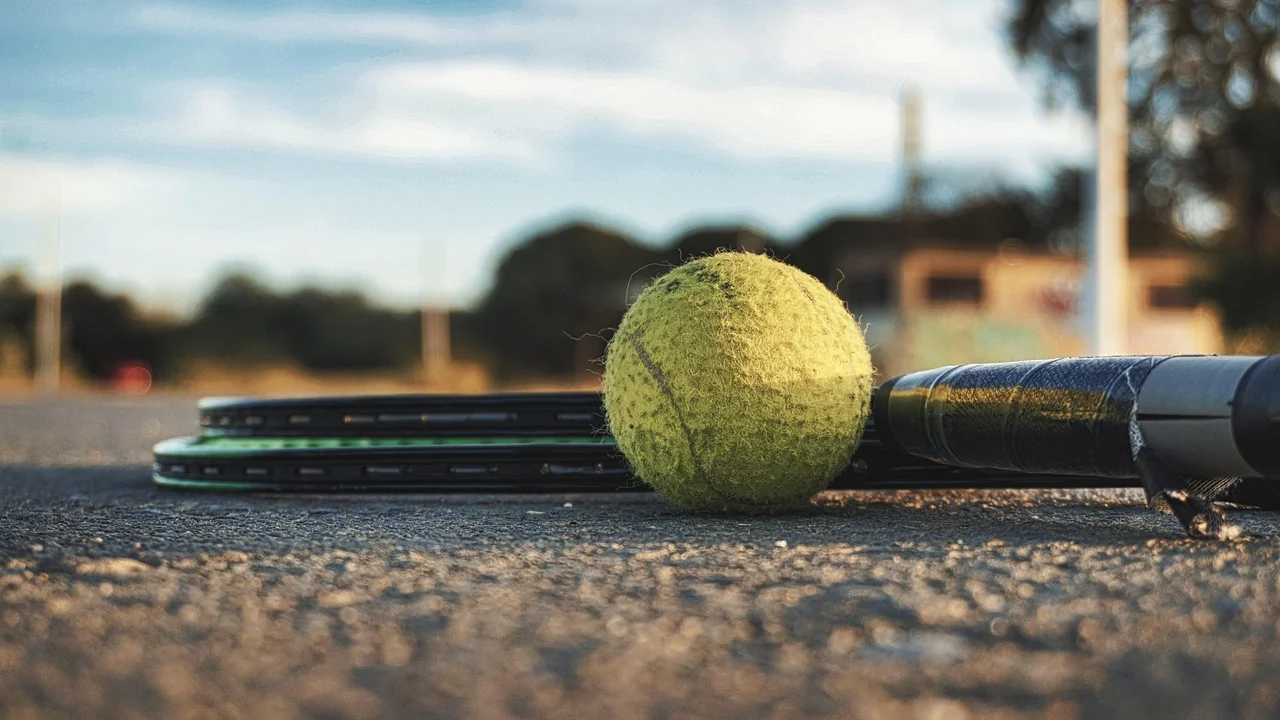 Raquete e bolas sobre uma quadra de tênis antes do treino.