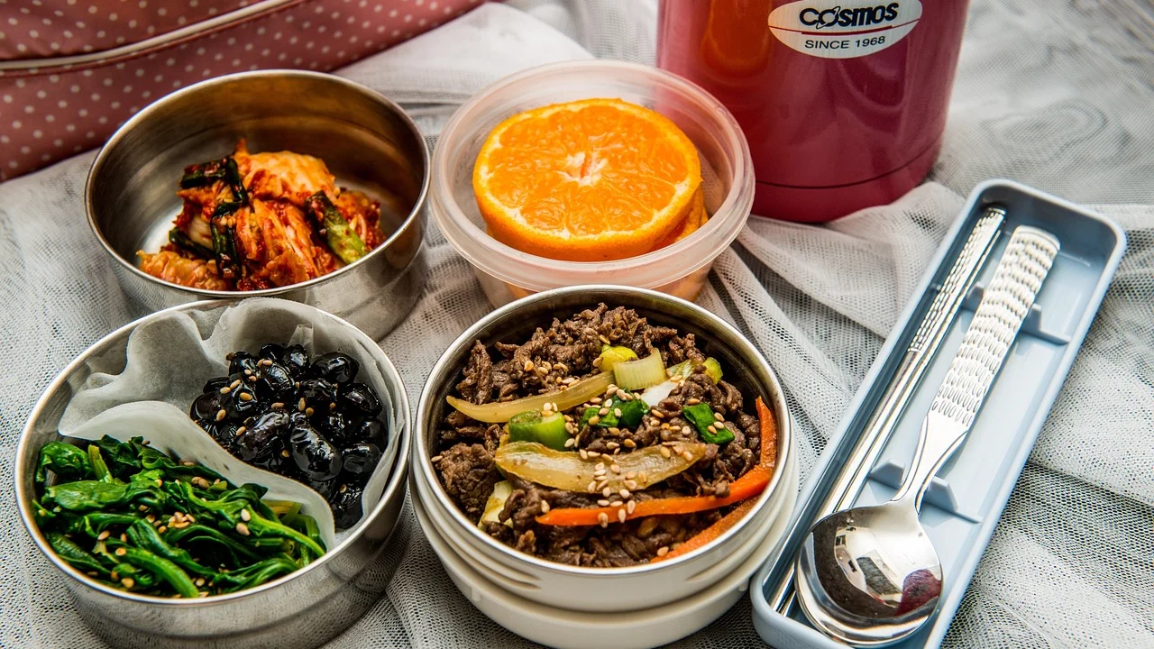 Marmita com arroz, feijão, proteína e legumes para o almoço no trabalho.
