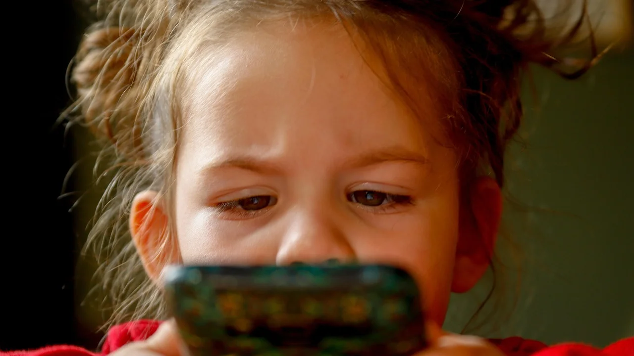 Criança usando o smartphone com acompanhamento de um adulto.