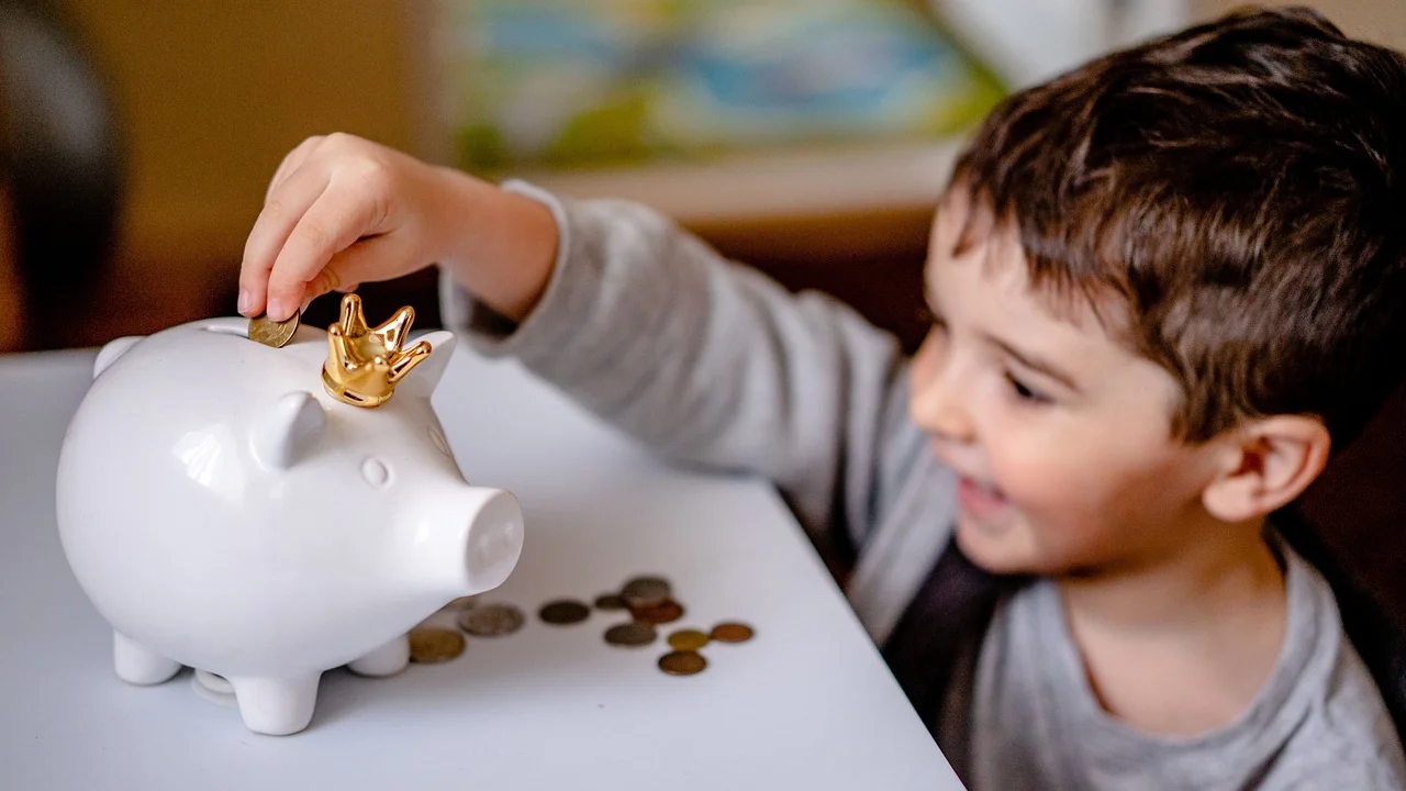 Criança separa moedas em potes para diferentes objetivos.