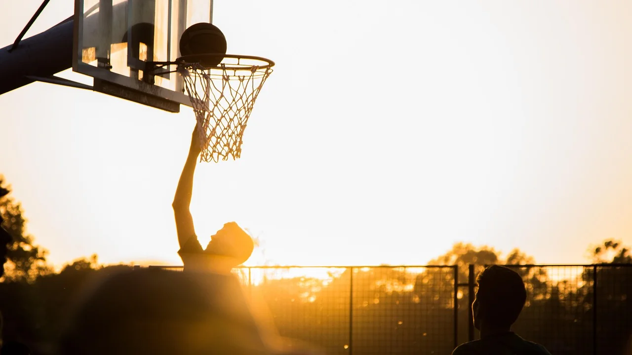 Jogador arremessa a bola durante uma partida de basquete