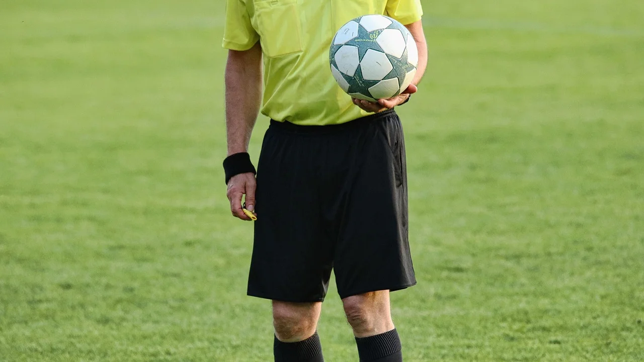 Árbitro acompanha uma disputa de bola no meio-campo.