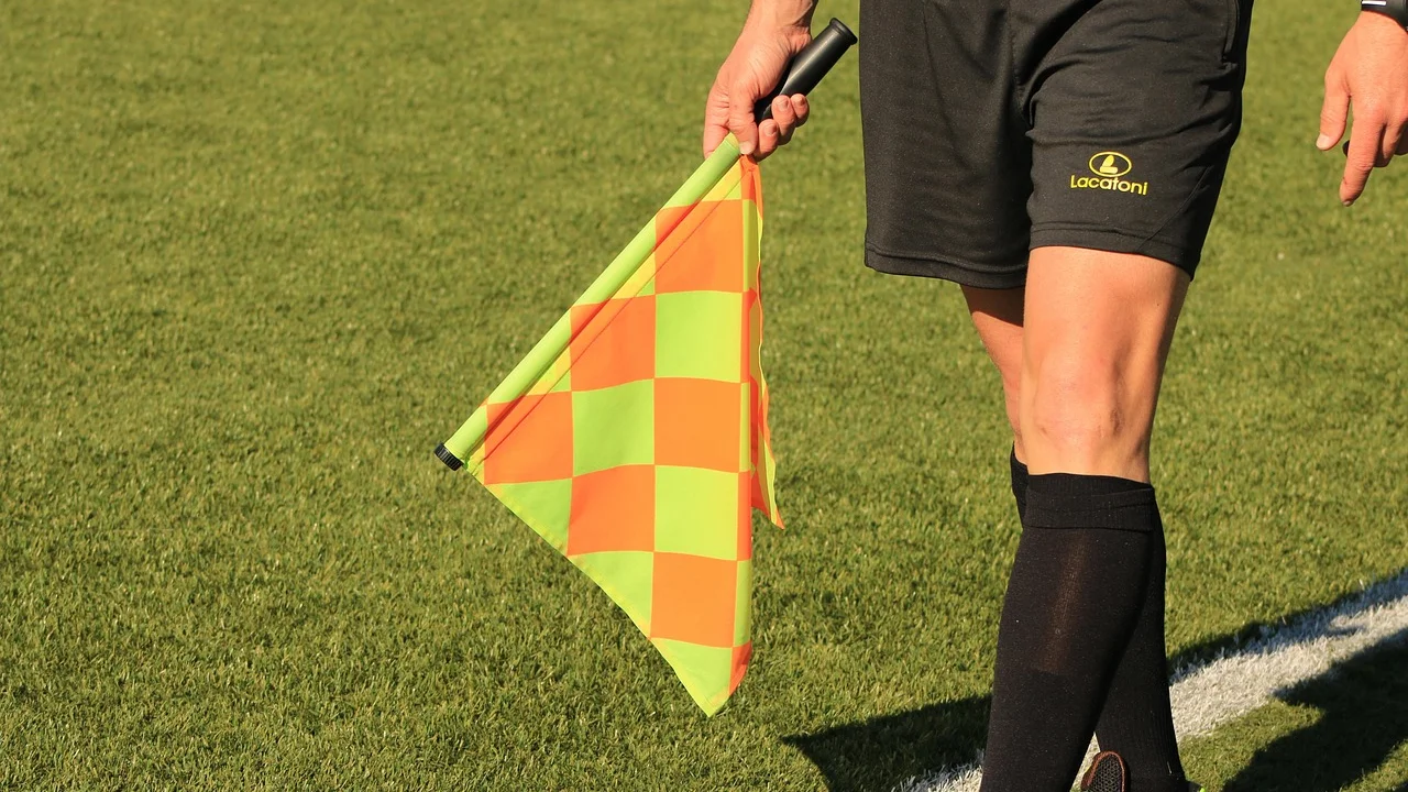 Assistente sinaliza um lance durante partida de futebol.
