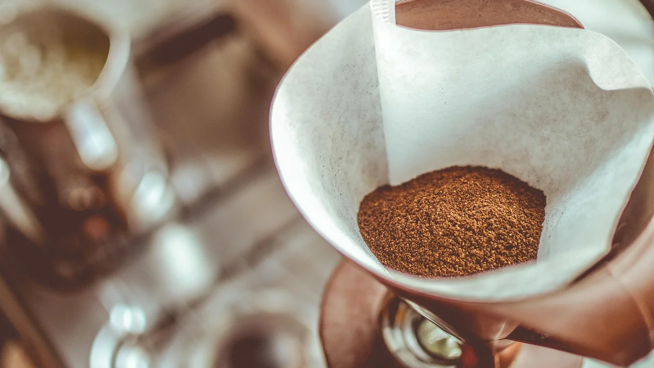 Café moído sendo colocado em filtro de papel limpo.