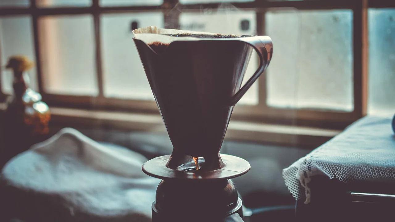 Água quente despejada lentamente sobre o café no coador.