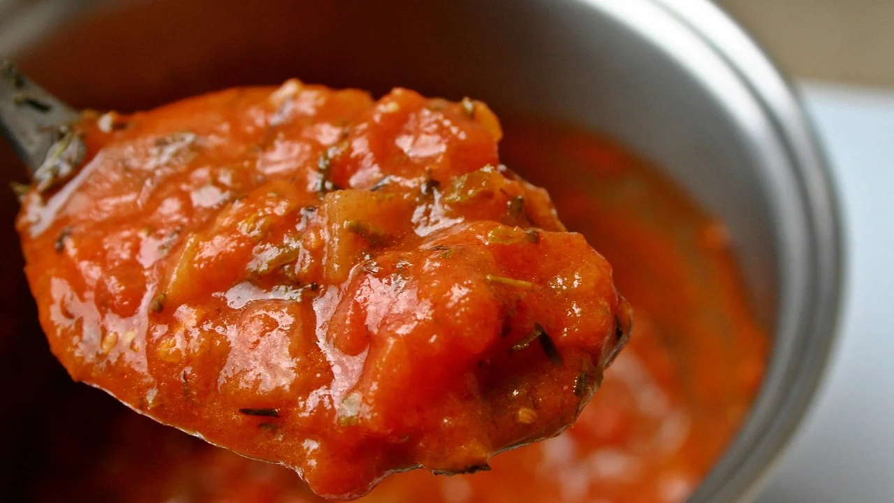 Tomates cozinhando lentamente em panela de fundo grosso.