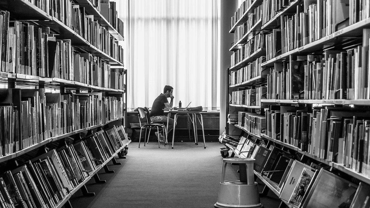Estudante consulta livros e materiais para pesquisa escolar.