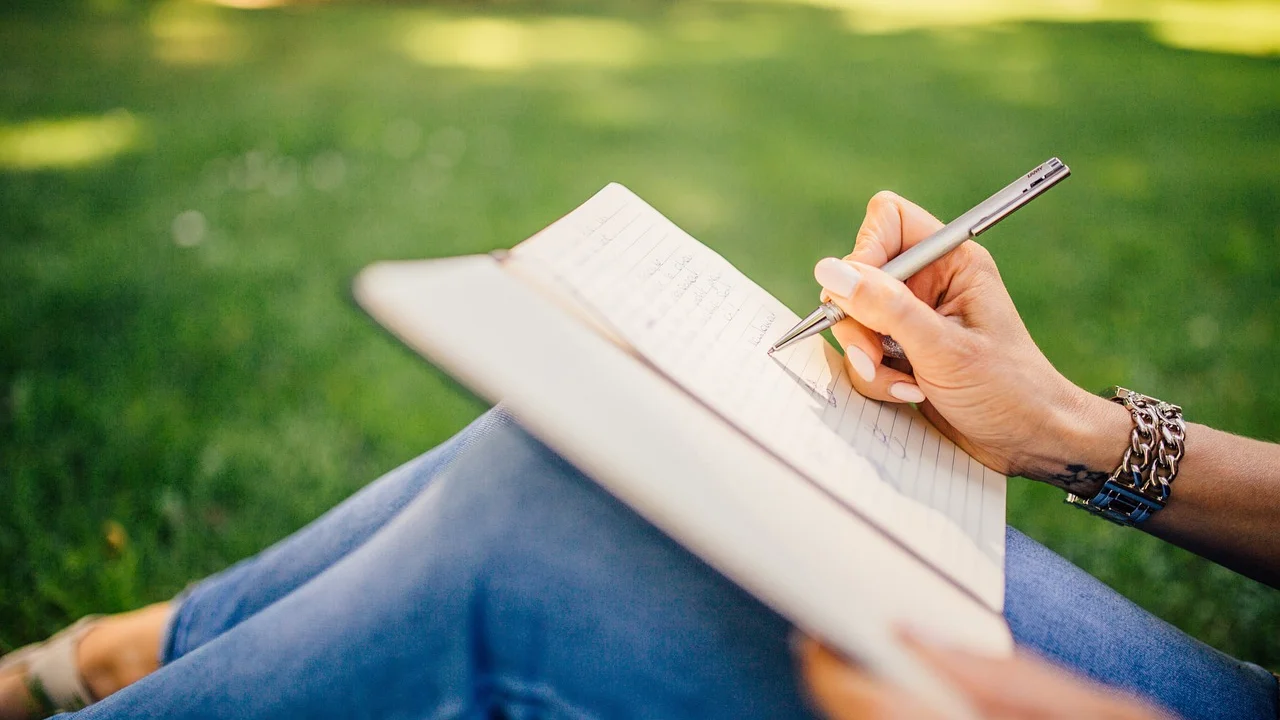 Pessoa praticando letras em um caderno pautado.