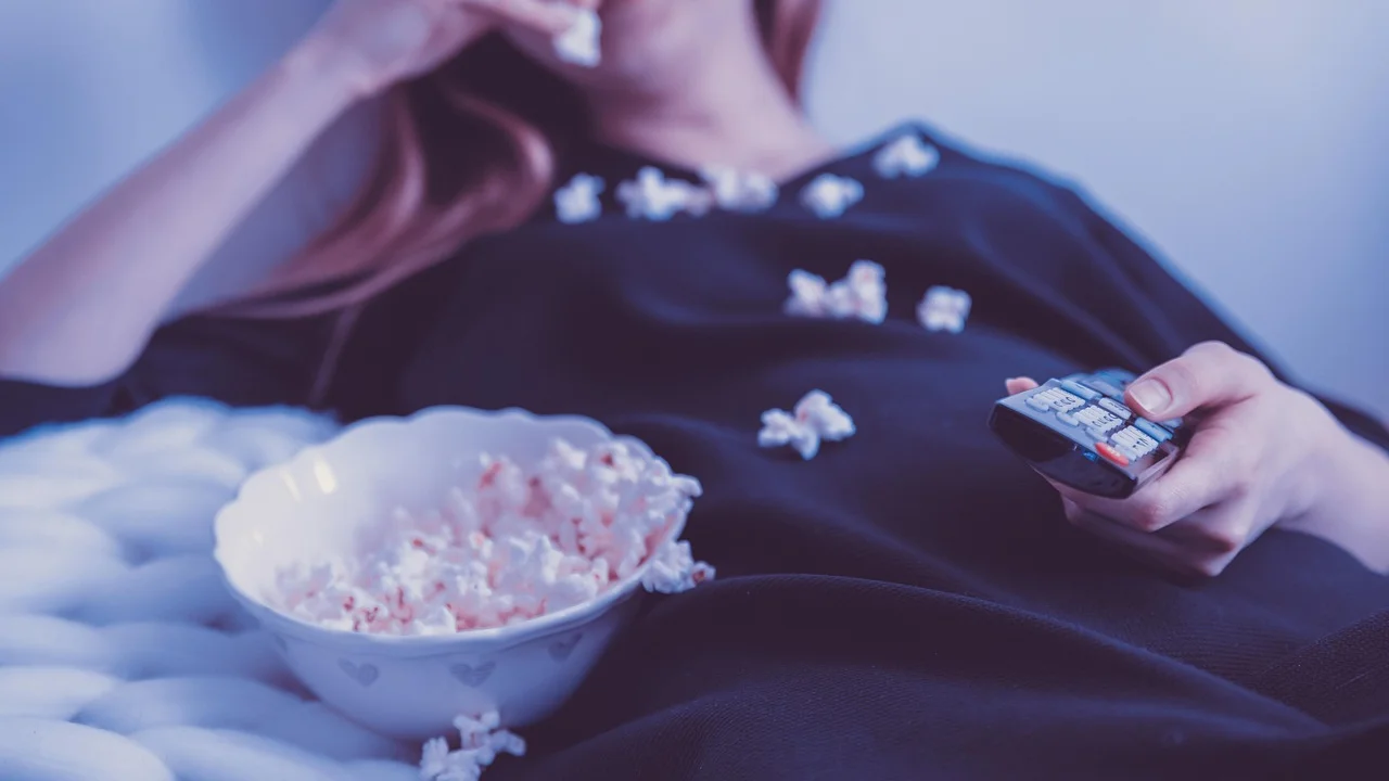 Controle remoto e pipoca preparados para uma sessão de séries