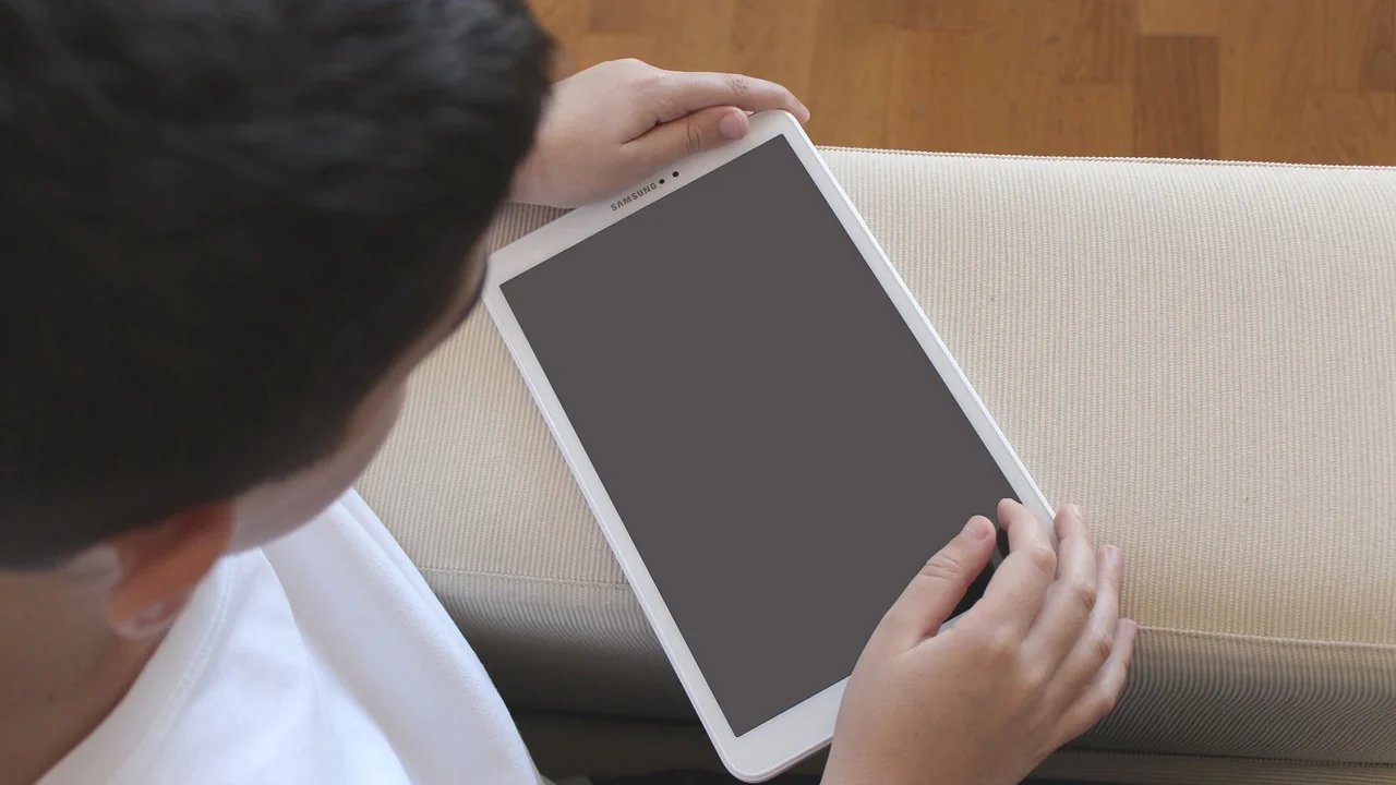Criança usa tablet com acompanhamento de um adulto.