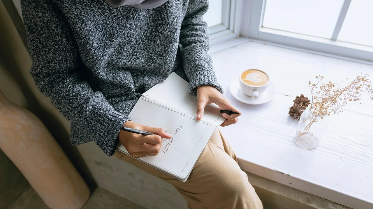 Pessoa anotando gatilhos e metas em um caderno