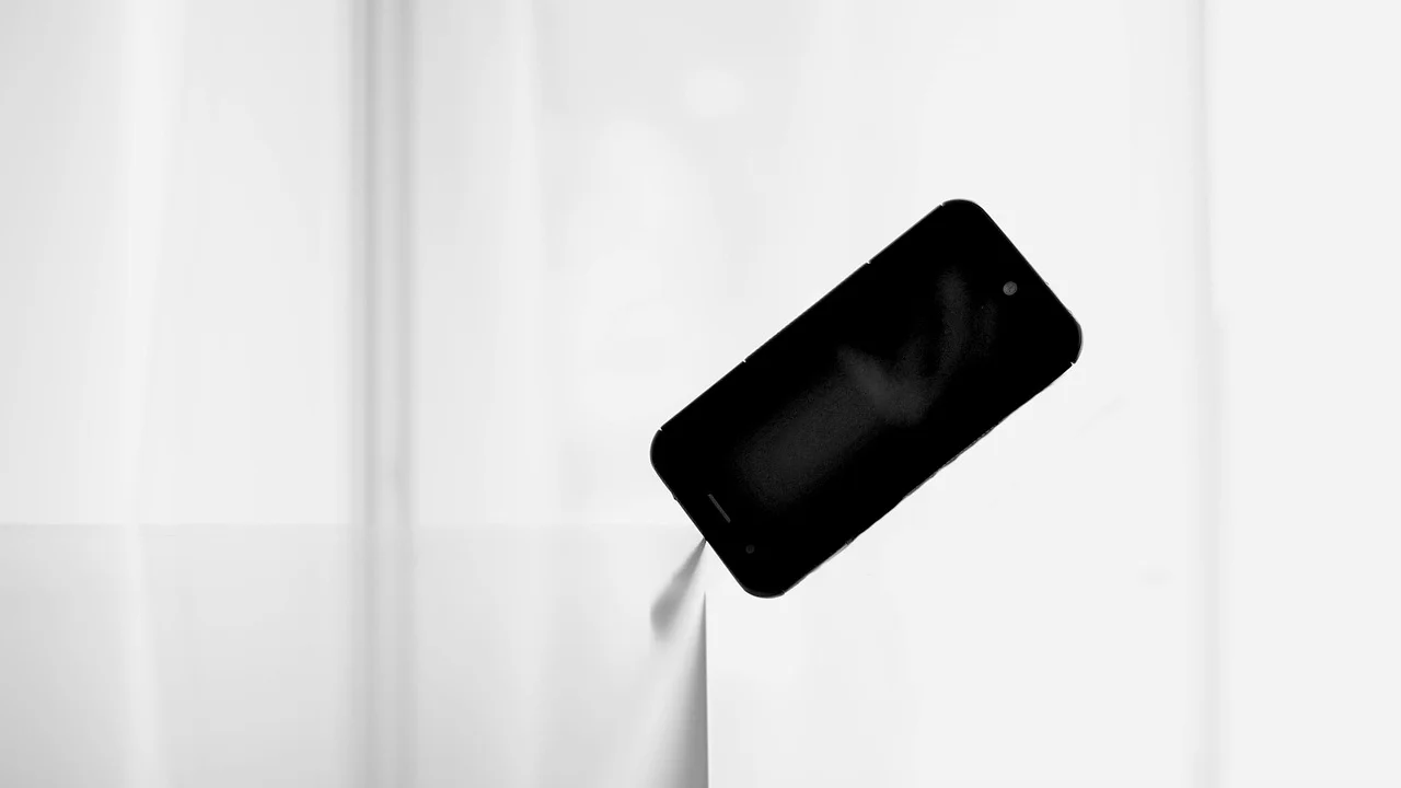 Celular sobre uma mesa ao lado de um livro aberto