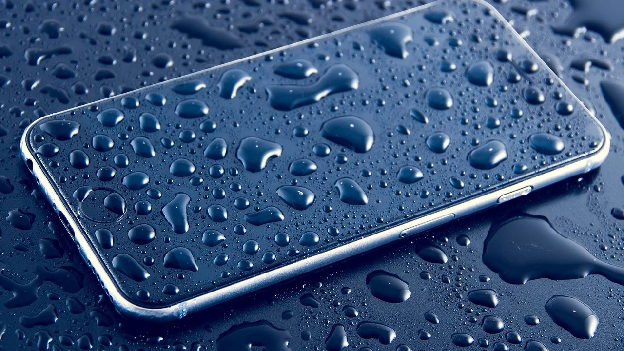 Celular molhado sendo retirado de uma superfície com água