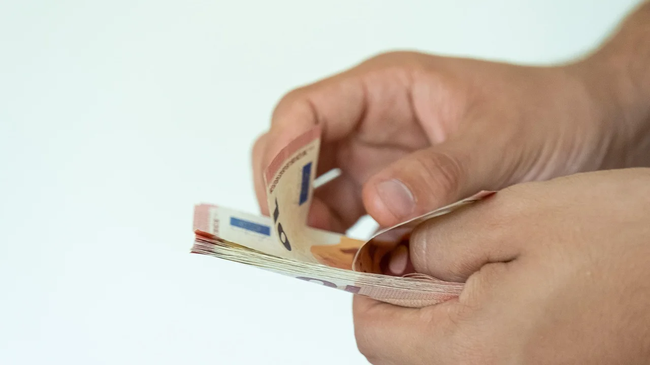Caderno de orçamento ao lado de calculadora e carteira.