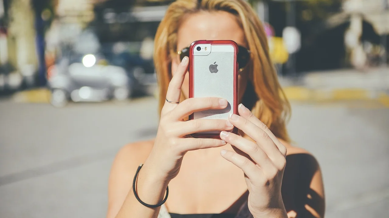 Detalhe de lente de smartphone sendo limpa com pano de microfibra.