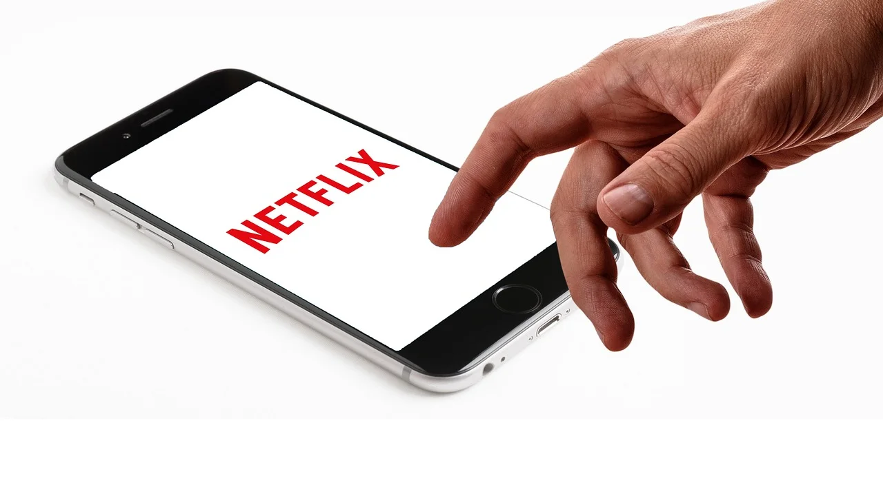 Smartphone exibindo botões de controle remoto ao lado de uma TV