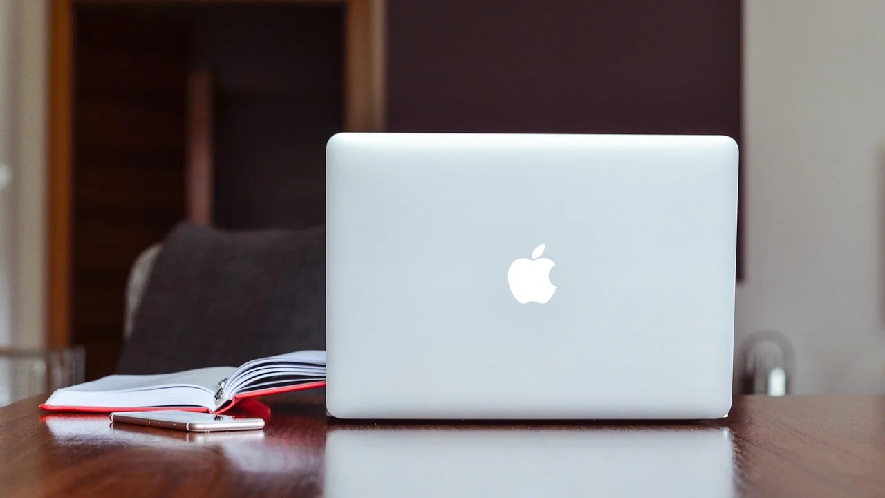 Notebook aberto em mesa de trabalho com acessórios externos.